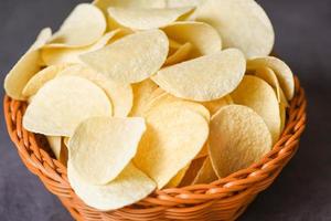 Crispy potato chips on the food table black background, Potato chips snack on basket photo