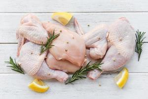 Breast wings and legs uncooked chicken meat marinated with ingredients for cooking - Fresh raw chicken with rosemary lemon herbs and spices photo