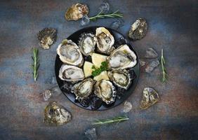 Oyster shell with herb spices lemon rosemary served table and ice healthy sea food raw oyster dinner in the restaurant gourmet food Fresh oysters seafood on plate black background photo