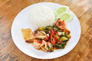 Stir fried seafood squid shrimp prawn with holy basil and rice - Thai food spicy fried recipe with cucumber and chili photo