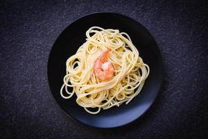 espaguetis pasta italiana con camarones camarones servidos en un plato de fondo negro - comida italiana y concepto de menú espaguetis mariscos foto