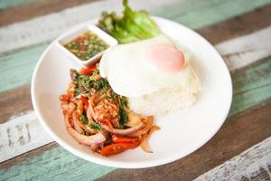 Rice topped with stir fried pork beef meat with holy basil and fried egg - Thai food spicy fried recipe with vegetables and chili sauce photo