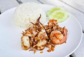 Pescado de calamar con camarones fritos con arroz en un plato blanco - mariscos fritos con ajo foto