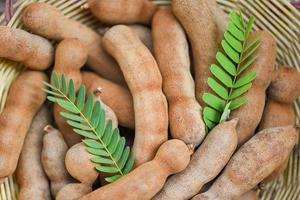 Tamarind in basket on the table background - fresh tamarind fruits and leaves photo