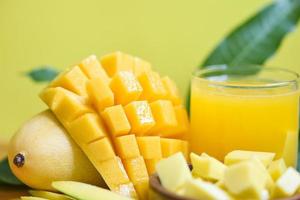 vaso de jugo de mango con rebanada de mango en hojas de mango del concepto de fruta de verano tropical de árbol - mangos maduros dulces foto