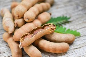 tamarindo y hojas de frutas tropicales - tamarindo dulce sobre fondo de madera foto