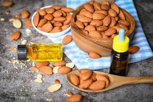 aceite de almendras y almendras sobre fondo oscuro, delicioso aceite de almendras dulces en botella de vidrio, nuez de almendra tostada para alimentos saludables y aceites vegetales orgánicos para cocinar o spa foto