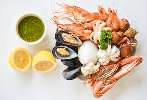 Fresh shrimps prawns squid mussels  spotted babylon shellfish crab and seafood sauce lemon on plate white background - Cooked food served seafood buffet concept photo