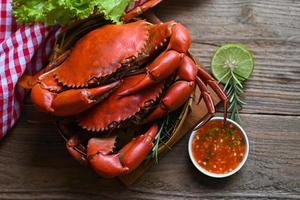 fresh crab on wooden and seafood sauce, seafood plate with herbs spices rosemary lemon lime salad lettuce vegetable, crab cooking food boiled or steamed crab red in the restaurant photo