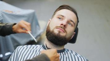 coiffeur peigne et coupe la barbe avec des ciseaux video