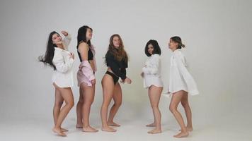 Group of young women dance and laugh together in underwear and oversized shirts video