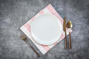 Coloque la comida en la mesa con un juego de platos blancos sobre manteles o una servilleta en la cena, un plato vacío, una cuchara, un tenedor y un cuchillo en la mesa. foto