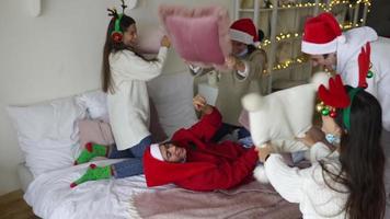 pessoas na festa de férias têm uma luta de travesseiros usando chapéus de Papai Noel e rindo em câmera lenta