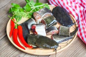 catfish fillet on wooden plate, fresh raw catfish menu freshwater fish, catfish for cooking food, fish chopped with ingredients herb and spices photo