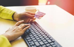 Business woman holding credit card payment and using keyboard computer in a office - payment online shopping paying with credit card technology e wallet concept photo