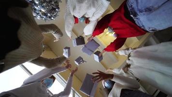 Group of people throw wrapped gifts in the air viewed from underneath in slow motion video