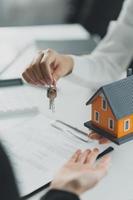 el agente inmobiliario o la agencia que entrega la llave de la casa al cliente después de firmar el contrato de acuerdo. concepto de propiedad. foto