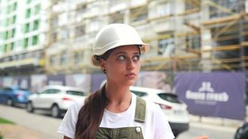 vrouw in wit moeilijk hoed in bouw zone denkt en looks kant naar kant video