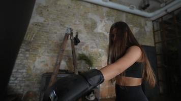 Slow motion of woman hitting punching bag with boxing gloves video