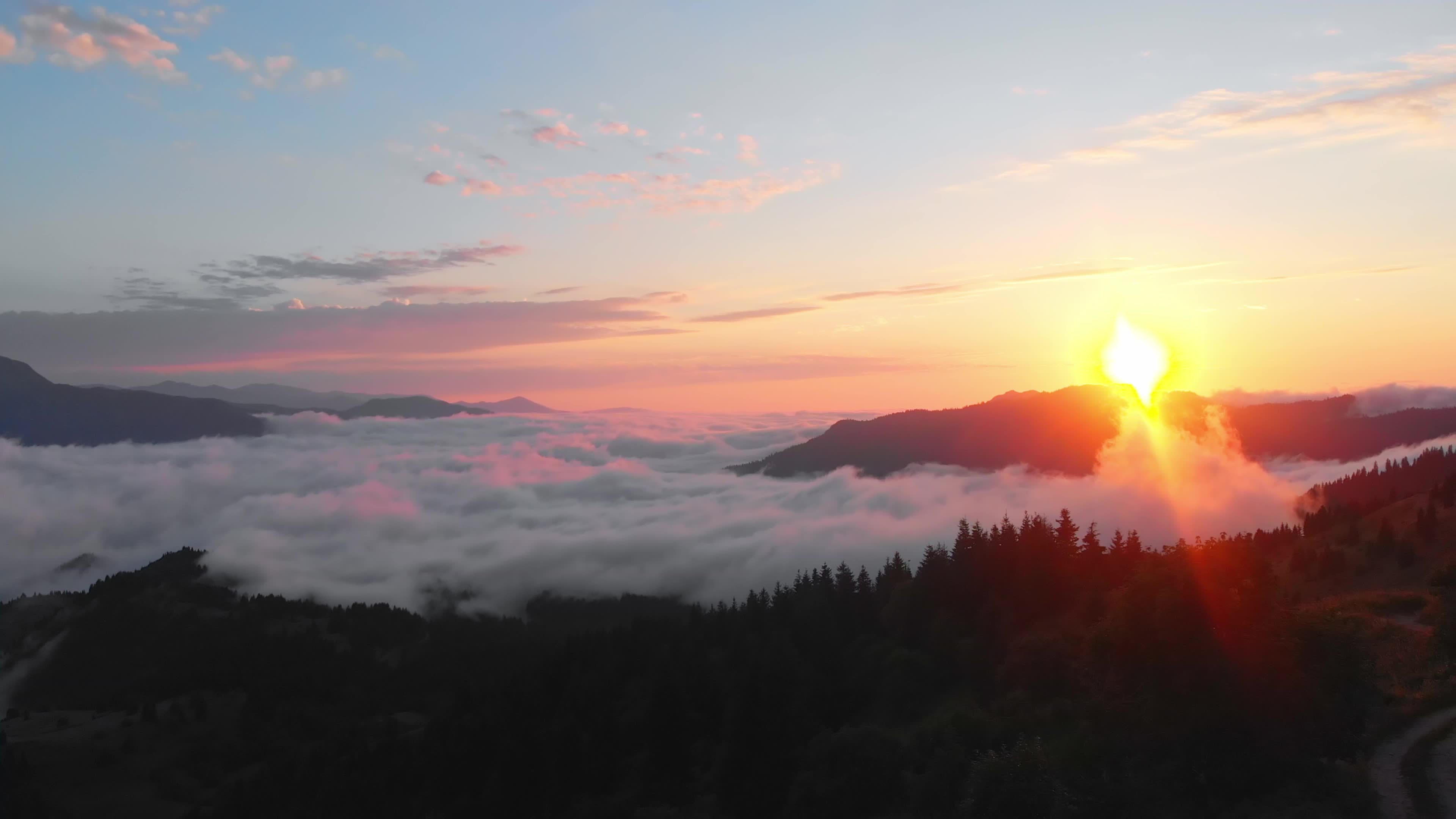 Static aerial panoramic view of sun rising above horizon with clouds