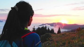 einsame Frau Porträt beobachten Sonnenuntergang im Freien über Wolken Mädchen Reisenden auf der Spitze des Berges in Strahlen des Sonnenuntergangs. Wanderer genießt die Natur video