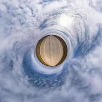 tiny planet in blue sky with sun and beautiful clouds. Transformation of spherical panorama 360 degrees. Spherical abstract aerial view. Curvature of space. photo