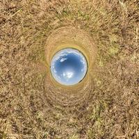 inversión de la transformación del pequeño planeta azul del panorama esférico de 360 grados. vista aérea abstracta esférica en el campo amarillo con impresionantes nubes hermosas. curvatura del espacio. foto