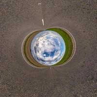 Inversion of blue little planet transformation of spherical panorama 360 degrees. Spherical abstract aerial view on road with awesome beautiful clouds. Curvature of space. photo