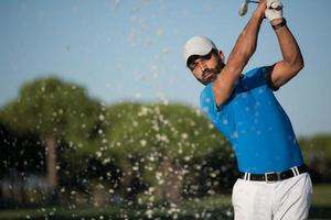 golfista profesional golpeando un tiro de búnker de arena foto