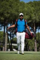 golf player walking and carrying bag photo