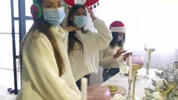 Menschen auf einer Weihnachtsfeier feiern zusammen mit festlichen Hüten und Masken um einen geschmückten Tisch video