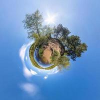 Little planet transformation of spherical panorama 360 degrees. Spherical abstract aerial view in field with clear sky and awesome beautiful clouds. Curvature of space. photo