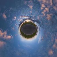 tiny planet in blue sky with sun and beautiful clouds. Transformation of spherical panorama 360 degrees. Spherical abstract aerial view. Curvature of space. photo