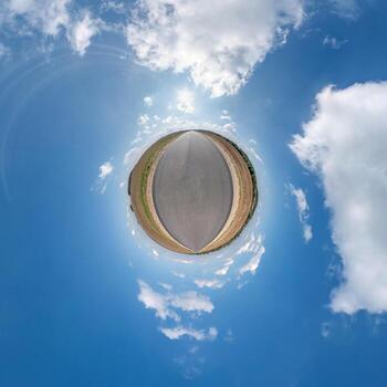 tiny planet with road in blue sky with beautiful clouds. Transformation of spherical panorama 360 degrees. Spherical abstract aerial view. Curvature of space. photo