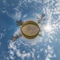 tiny planet in blue sky with beautiful clouds. Transformation of spherical panorama 360 degrees. Spherical abstract aerial view. Curvature of space. photo