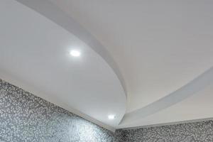 Detail of corner ceiling with intricate crown molding. Suspended ceiling and drywall construction in empty room in apartment or house. Stretch ceiling white and complex shape. photo