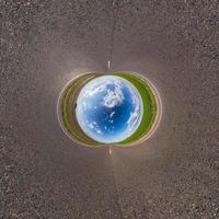 Inversion of blue little planet transformation of spherical panorama 360 degrees. Spherical abstract aerial view on road with awesome beautiful clouds. Curvature of space. photo