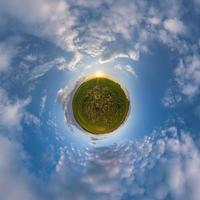 tiny planet in blue evening sky with beautiful clouds. Transformation of spherical panorama 360 degrees. Spherical abstract aerial view. Curvature of space. photo