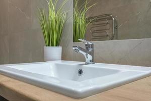 metal water tap sink with faucet in expensive bathroom. detail of a corner toilet with wall mount shower attachment photo