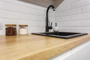 fregadero de agua negra con grifo y dispensador de jabón en la costosa cocina tipo loft foto