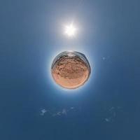 yellow sand tiny planet in blue sky with beautiful clouds. Transformation of spherical panorama 360 degrees. Spherical abstract aerial view. Curvature of space. photo