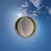 tiny planet in blue sky with beautiful clouds. Transformation of spherical panorama 360 degrees. Spherical abstract aerial view. Curvature of space. photo