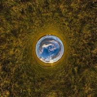 Inversion of little planet transformation of spherical panorama 360 degrees. Spherical abstract aerial view on field with awesome beautiful clouds. Curvature of space. photo