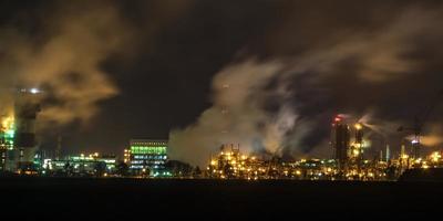 night industrial landscape environmental pollution waste of thermal power plant. Big pipes of chemical industry enterprise plant photo
