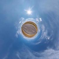 tiny planet in blue sky with sun and beautiful clouds. Transformation of spherical panorama 360 degrees. Spherical abstract aerial view. Curvature of space. photo