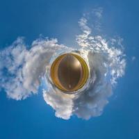 tiny planet in blue sky with beautiful clouds. Transformation of spherical panorama 360 degrees. Spherical abstract aerial view. Curvature of space. photo