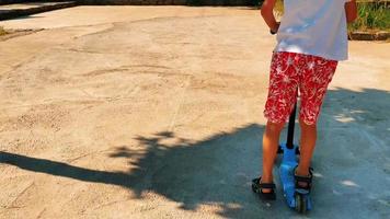 adolescent monte un scooter dans le parc par beau temps clair video