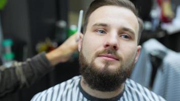 barbeiro gira cliente masculino com cabelo curto e barba na cadeira video