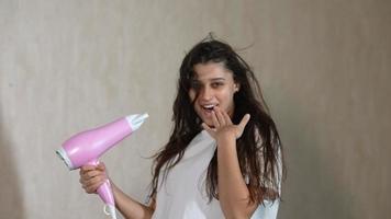 Woman blow drying hair posing smiling and dancing in slow motion video