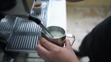 close-up nas mãos de barista leite fumegante em um copo de aço inoxidável video